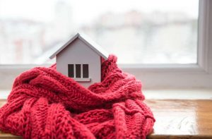 Casa in miniatura con la sciarpa, simbolo di abitazione al caldo