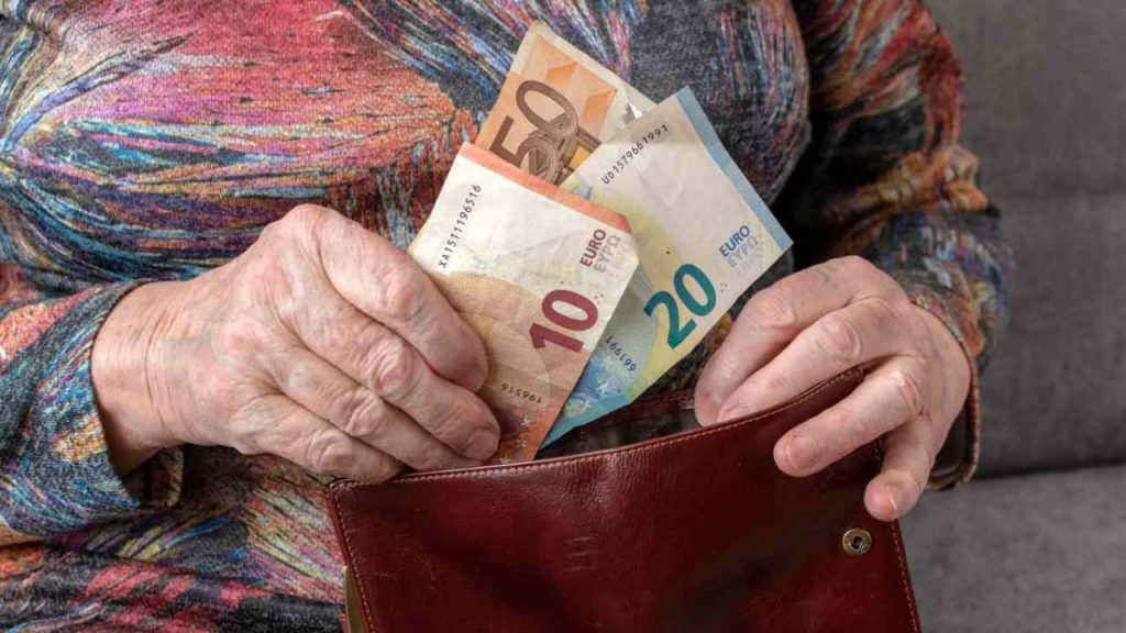 Persona anziana che tira fuori banconote euro dal portafoglio