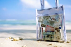 Borsa da mare sulla spiaggia piena di soldi