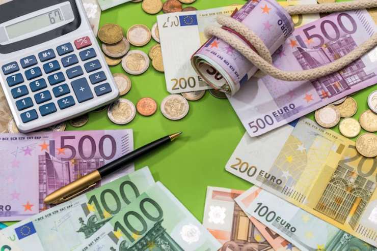 Calcolatrice, penna, monete e banconote euro