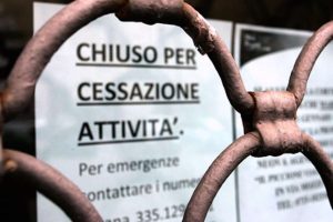 Cartello 'chiuso per cessata attività' e serrande chiuse