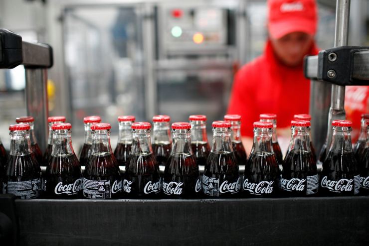 Bottiglie di Coca Cola sul carrello industriale e uomo in secondo piano